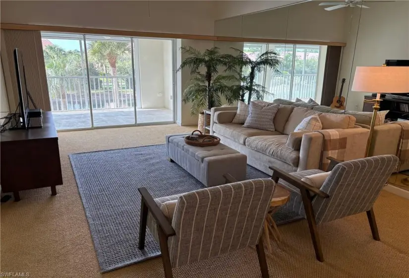 Carpeted living room with a healthy amount of sunlight, vaulted ceiling, and ceiling fan