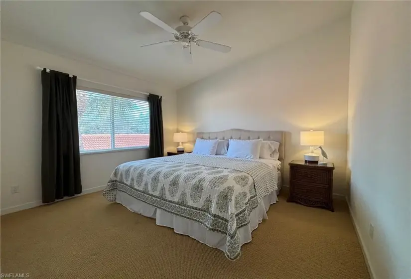 Carpeted bedroom featuring vaulted ceiling and ceiling fan