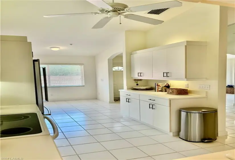 Kitchen featuring ceiling fan, stove, stainless steel refrigerator, and light tile floors