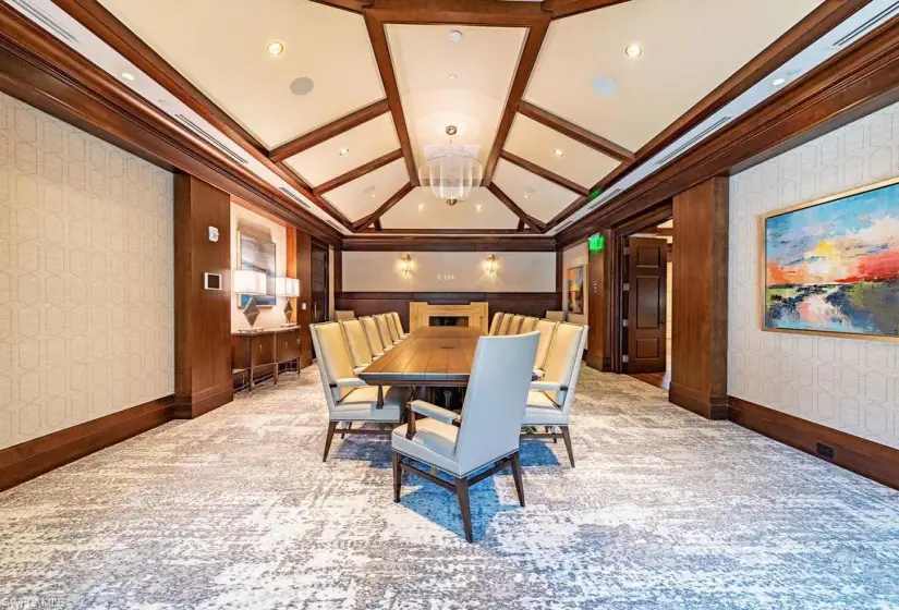 Carpeted dining area featuring vaulted ceiling, coffered ceiling, and crown molding