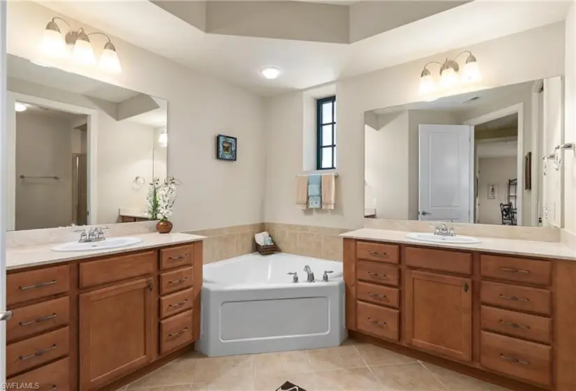 Bathroom with vanity with extensive cabinet space, double sink, and tile flooring