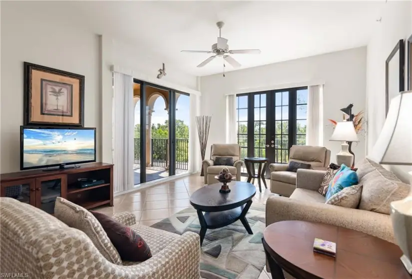 Tiled living room with ceiling fan and french doors