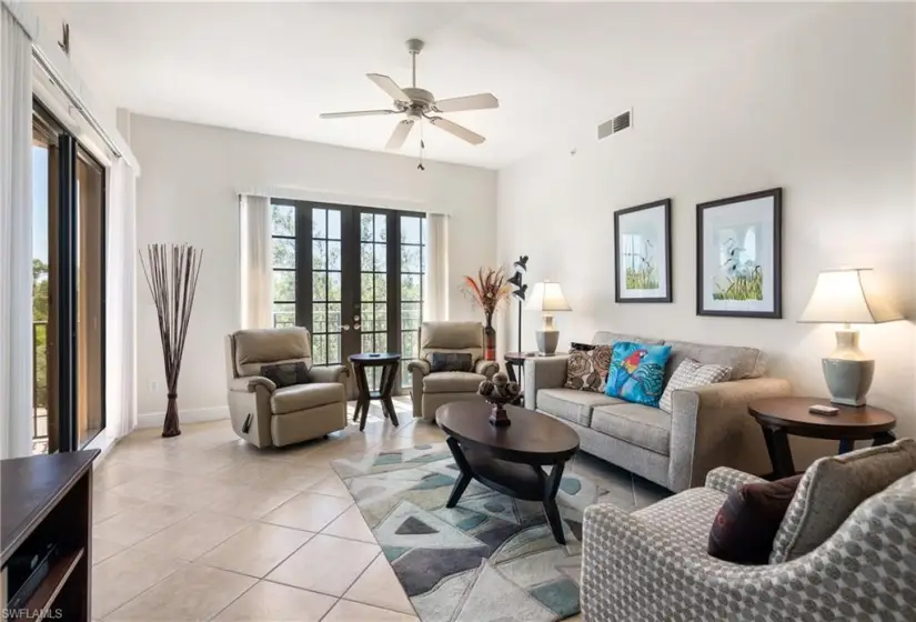 Living room featuring light tile floors, ceiling fan, and french doors