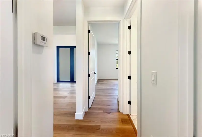 Hall with light hardwood / wood-style flooring between guest bedrooms