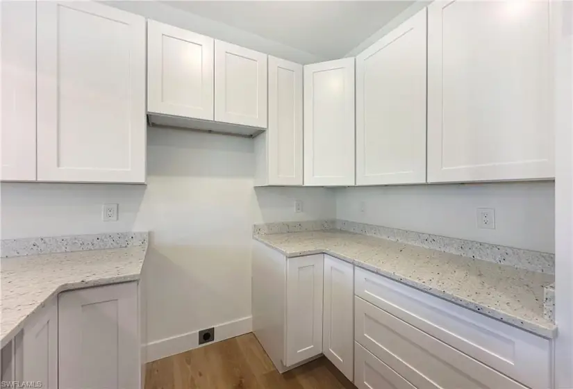 Kitchen featuring white cabinetry, light stone countertops, and light wood-type flooring