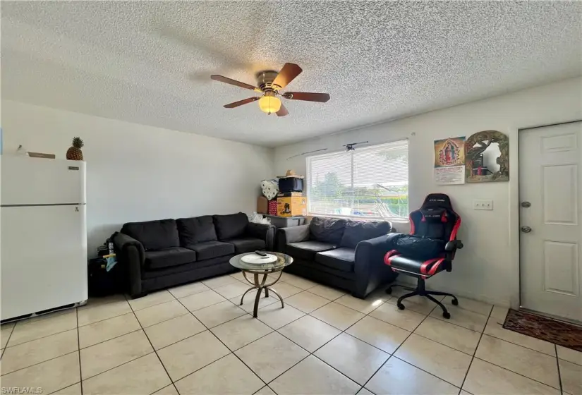 Living room featuring ceiling fan, a textured ceiling, and light tile floors