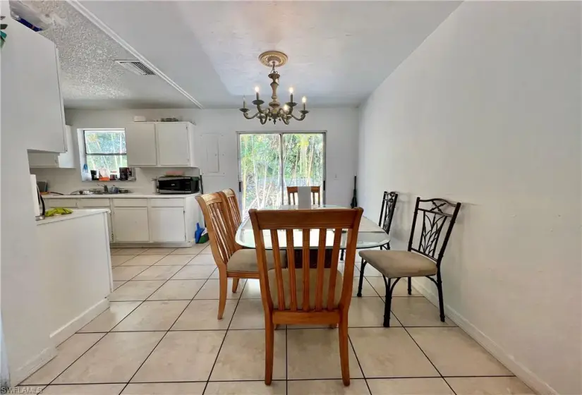 Tiled dining space featuring a notable chandelier, sink, a textured ceiling, and a wealth of natural light