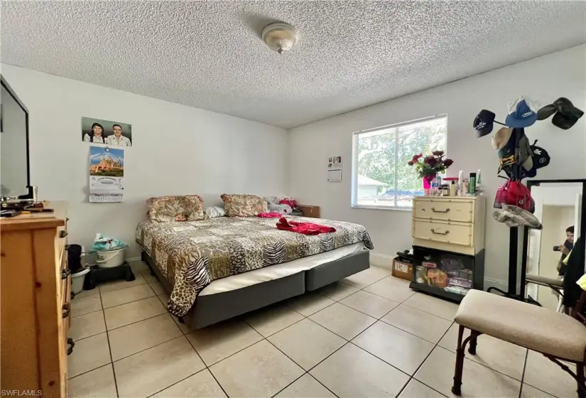 Bedroom featuring a textured ceiling and light tile floors