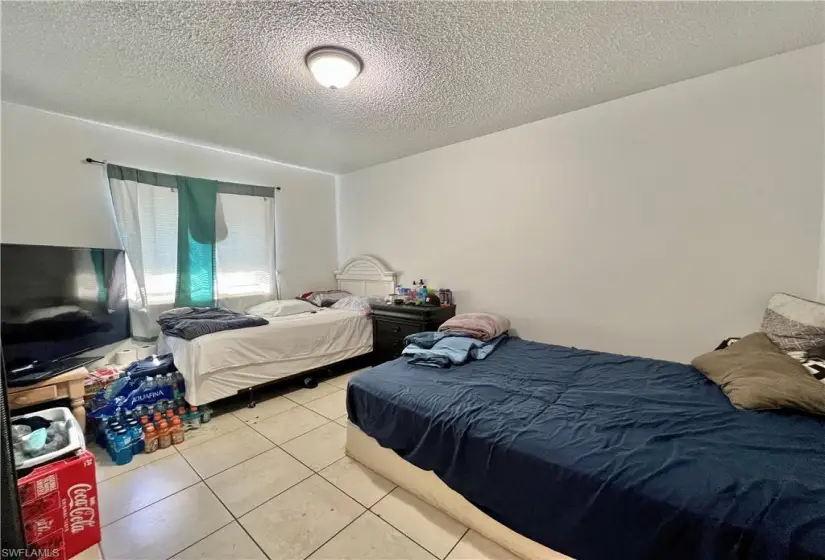 Tiled bedroom with a textured ceiling