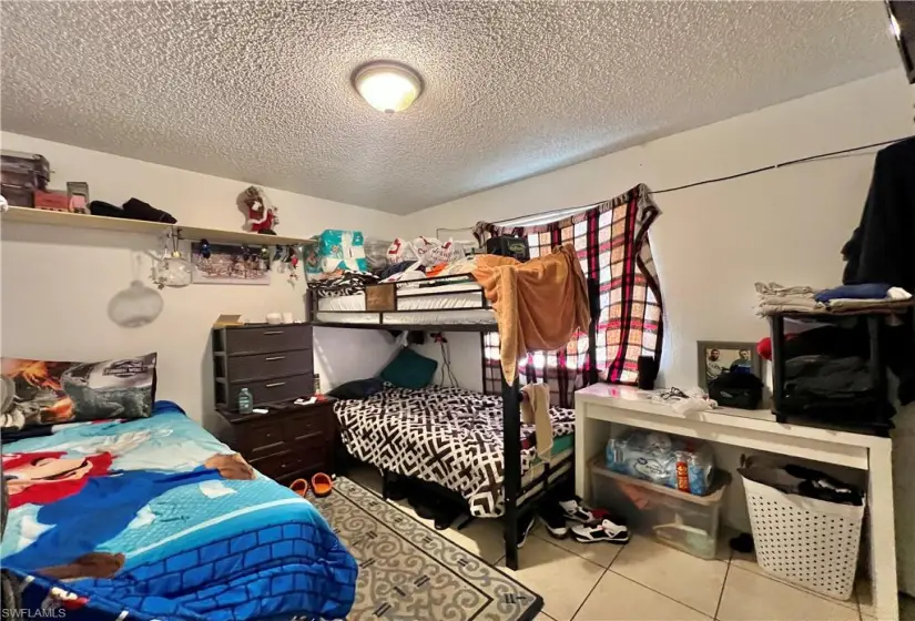 Bedroom with tile floors and a textured ceiling